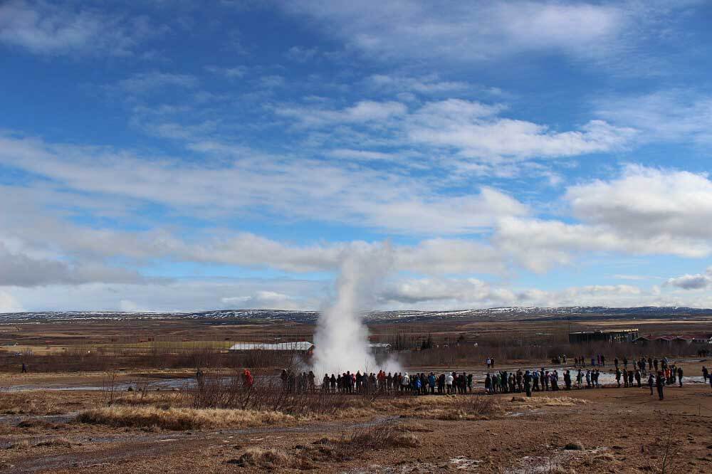Die Touristen versammeln sich um den Geysir, um dessen Ausbruch mitzuerleben.