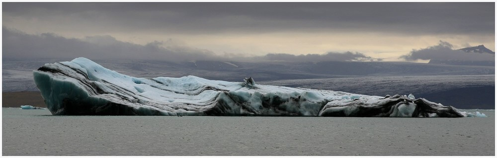 Die schwarzen Streifen auf diesem gewaltigen Eisberg sind gefrorene Vulkanasche