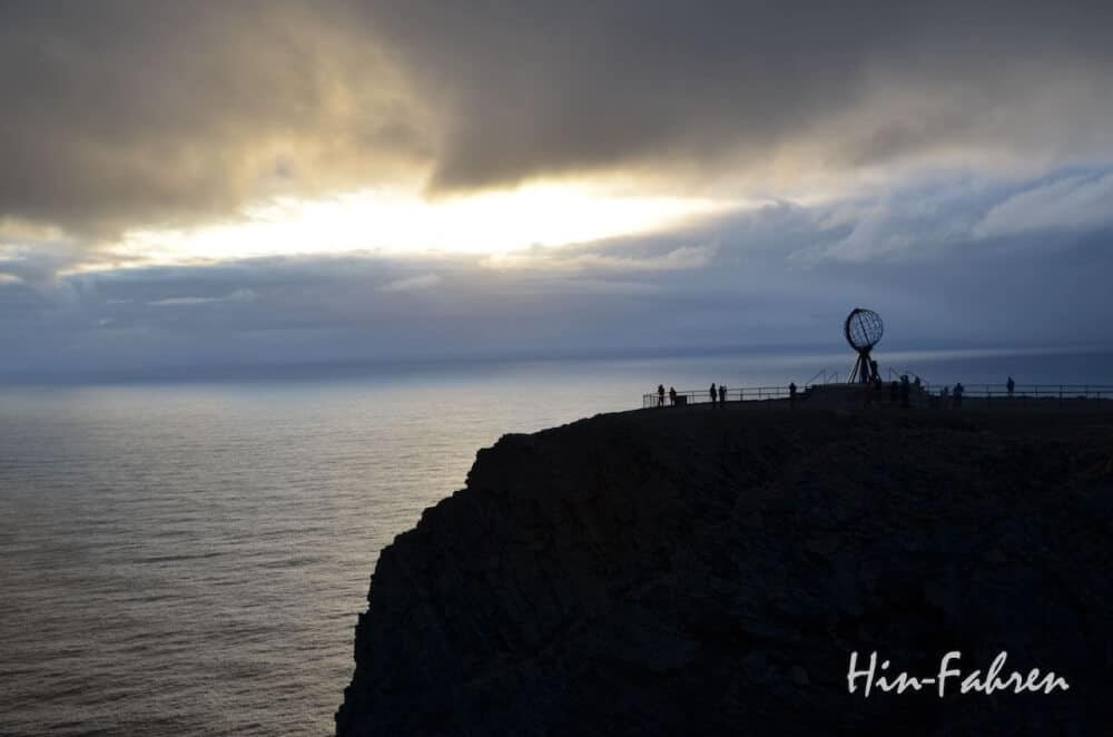 Mitternacht am Nordkap. Bei heftigem Sturm reißt kurz die Wolkendecke auf und die Mitternachtssonne erscheint.