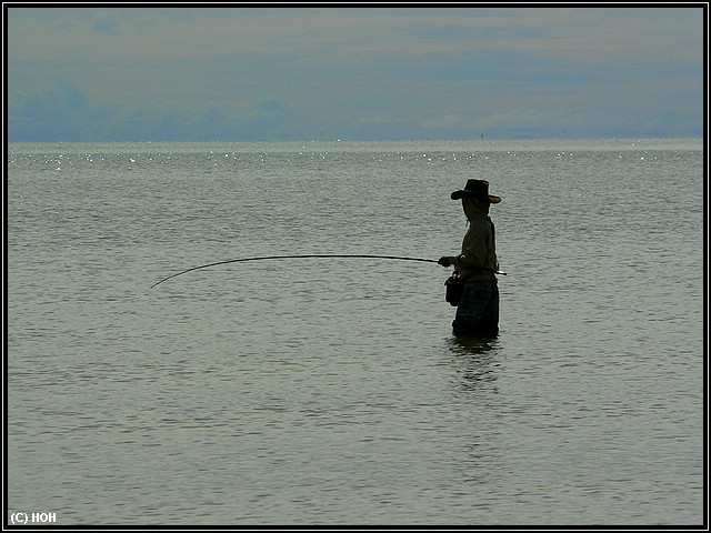 Angler steht im seichten Wasser